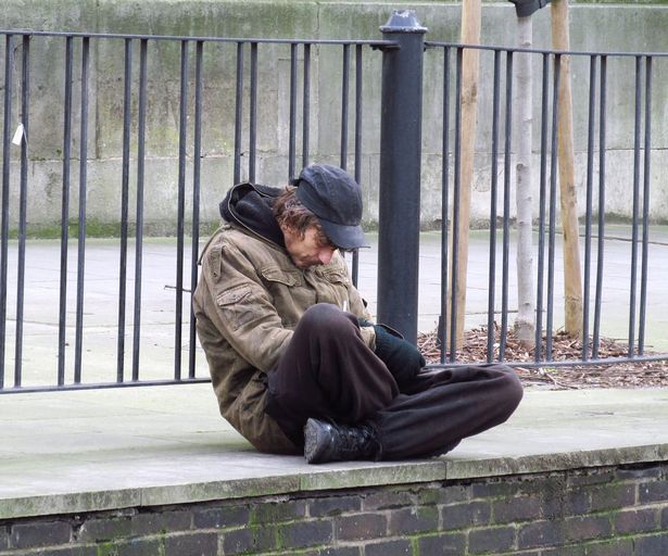 homeless man sitting by a railing